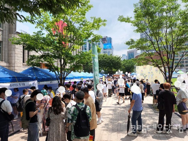 퀴어행사 부스들 앞에 청소년들과 청년들이 줄지어 어려 정보를 얻고 있다.