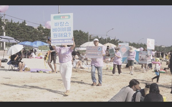 아름다운피켓 봉사 지원자들이 피켓을 들고 해수욕장 한 가운데를 가로지르며 캠페인을 벌이고 있다.