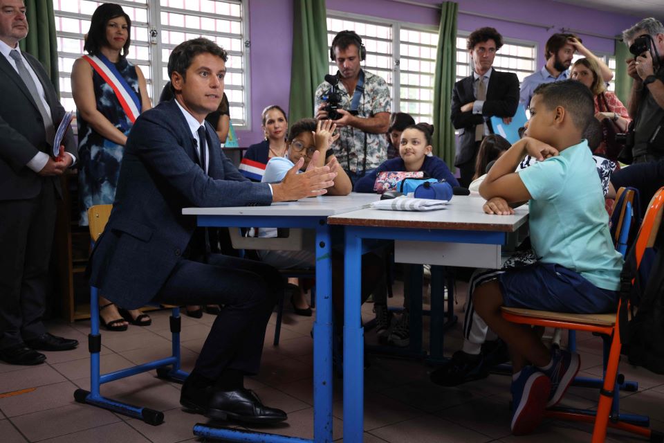 17일(현지시간) 한 초등학교를 방문한 가브리엘 아탈 장관(사진 왼쪽의 앉아 있는 남성) [AFP=연합뉴스]